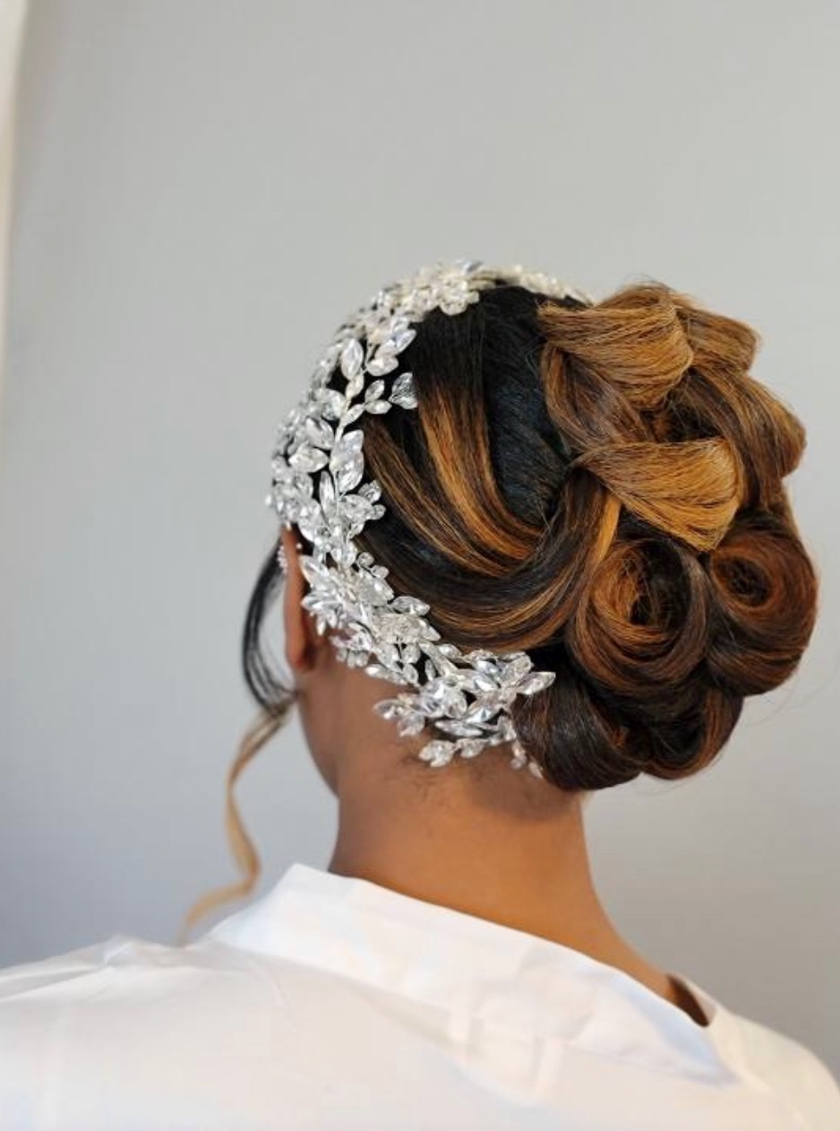 A woman from behind with an updo styled with a crystal floral tiara piece.