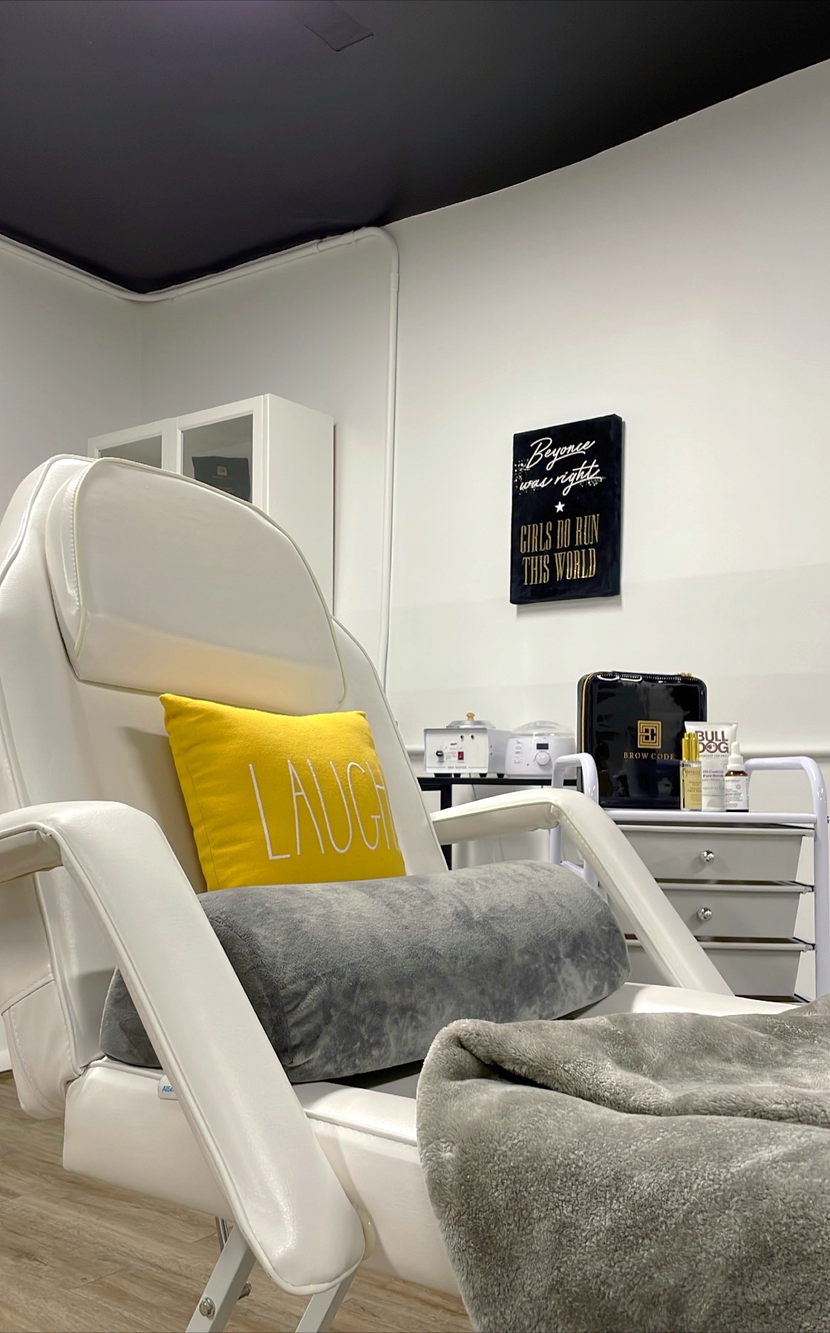 One of the salon chairs. It is a white reclining chair, with blankets and a yellow pillow that says "Laugh".