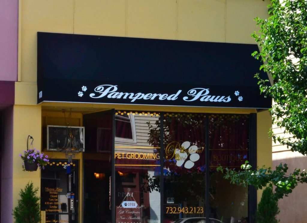 Pampered Paws store front, that has a black awning with white cursive text.