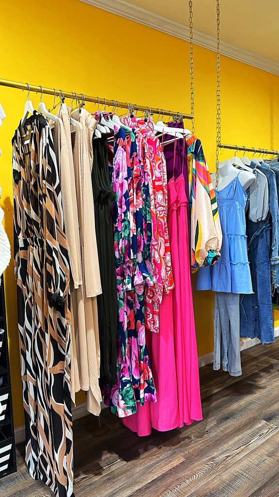 Racks with different types of dresses hanging, in various bright colors.