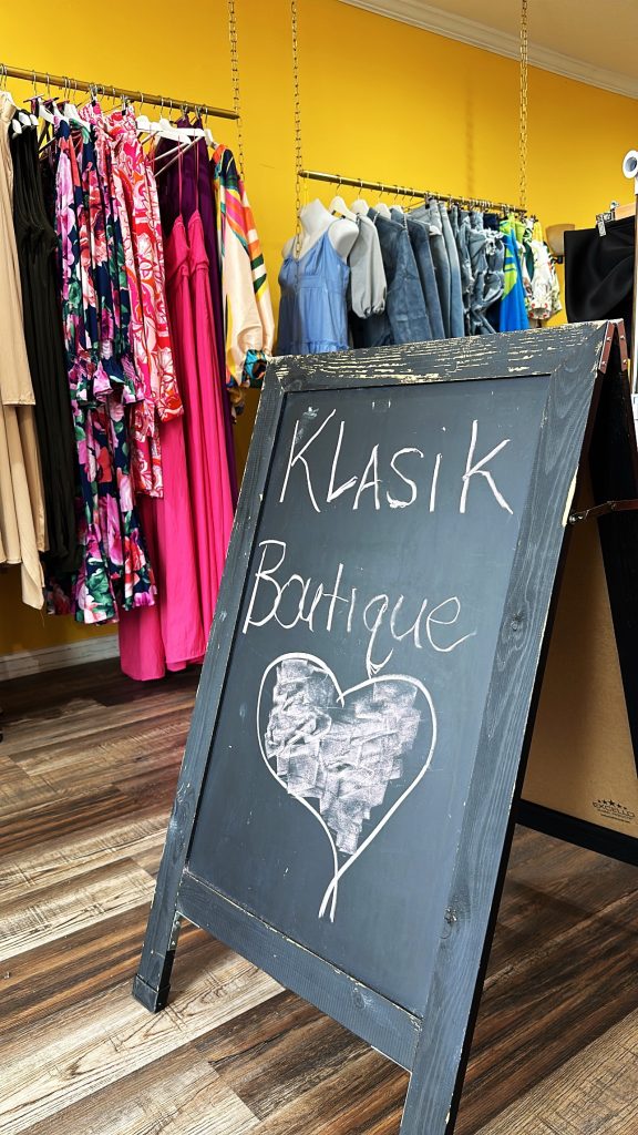An aframe chalkboard with Klasik Boutique written on it, with a heart drawn underneath.
